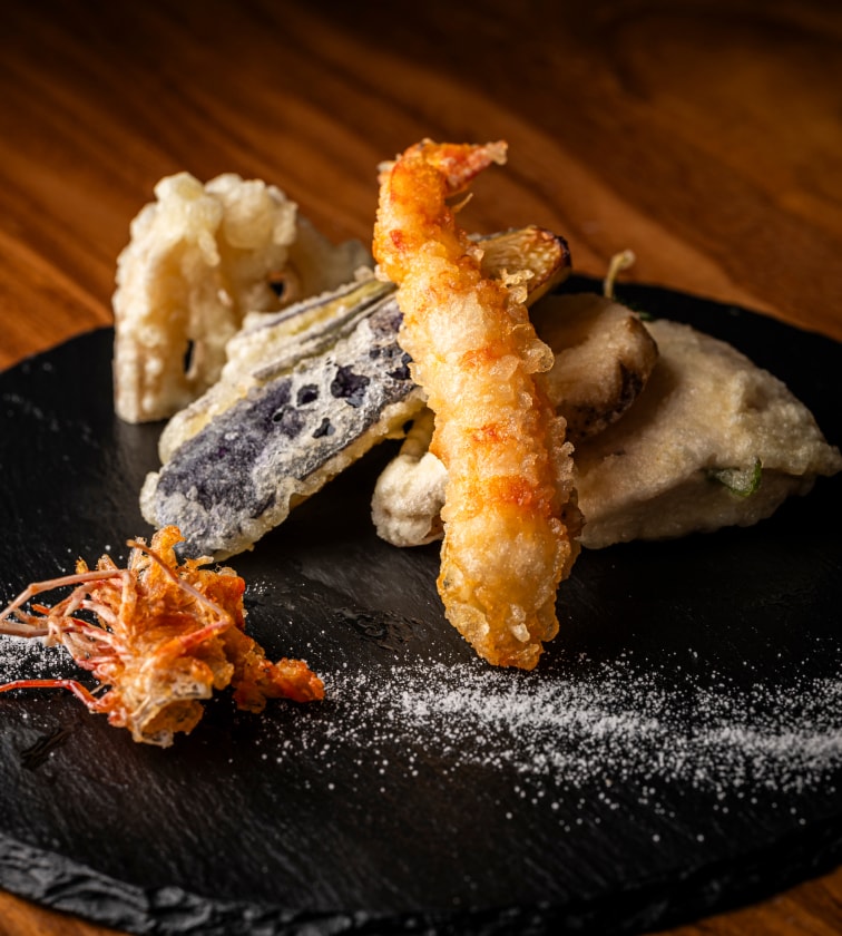 黒いお皿に塩と共に盛り付けられた天ぷら